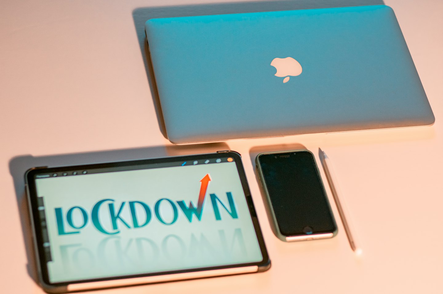 Laptop, tablet, and smartphone on a pink desk.