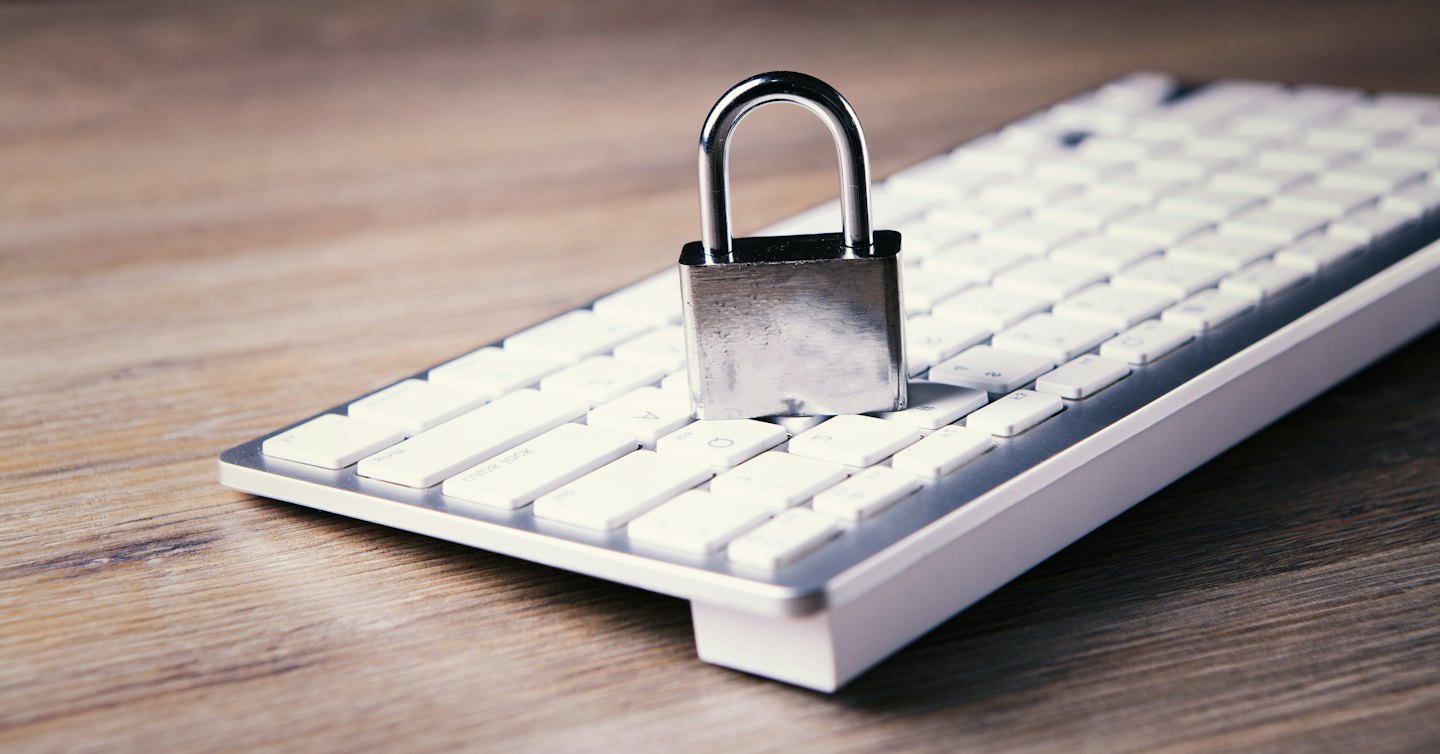 Silver padlock rests on a white computer keyboard.